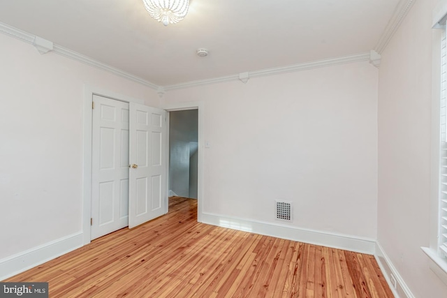 empty room with light wood-type flooring and crown molding