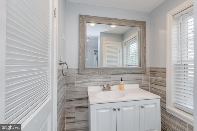 bathroom with a wealth of natural light, vanity, and tile walls