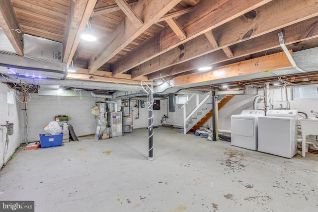 basement with heating unit, water heater, sink, and washing machine and clothes dryer