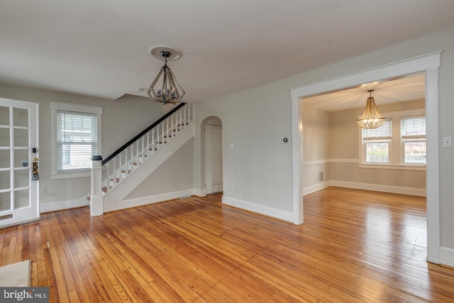 unfurnished living room featuring a chandelier, hardwood / wood-style floors, and a wealth of natural light