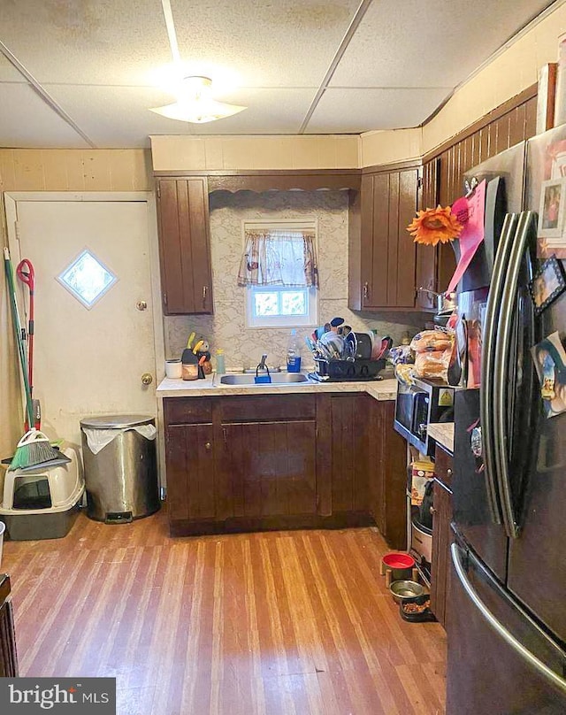 kitchen with a paneled ceiling, sink, light hardwood / wood-style floors, dark brown cabinetry, and stainless steel appliances