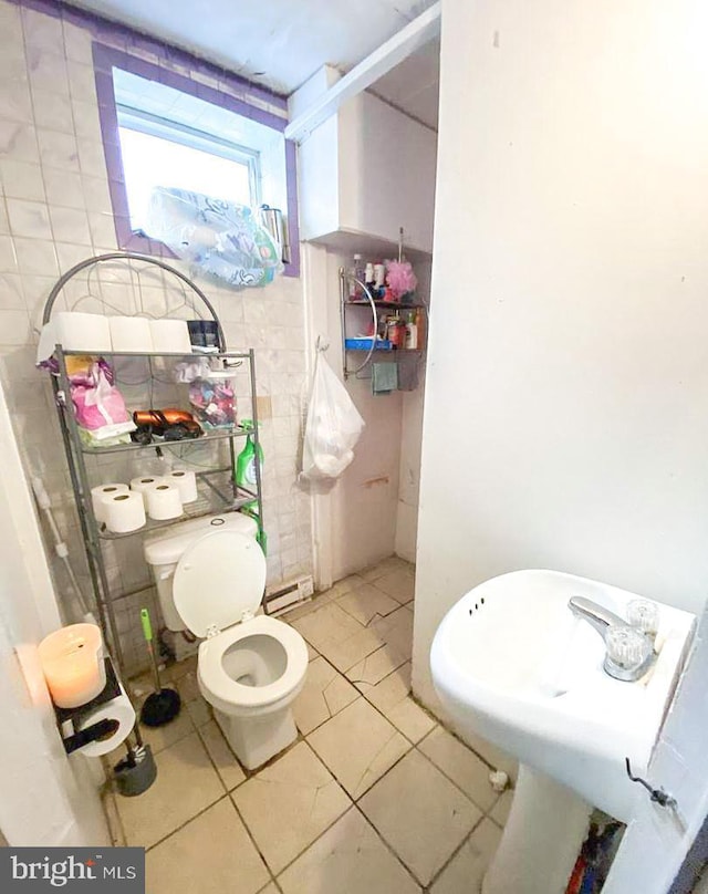 bathroom featuring tile patterned floors, baseboard heating, tile walls, and toilet