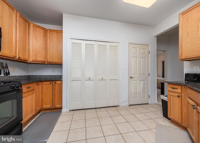 kitchen featuring black electric range oven, dark stone counters, and light tile patterned floors