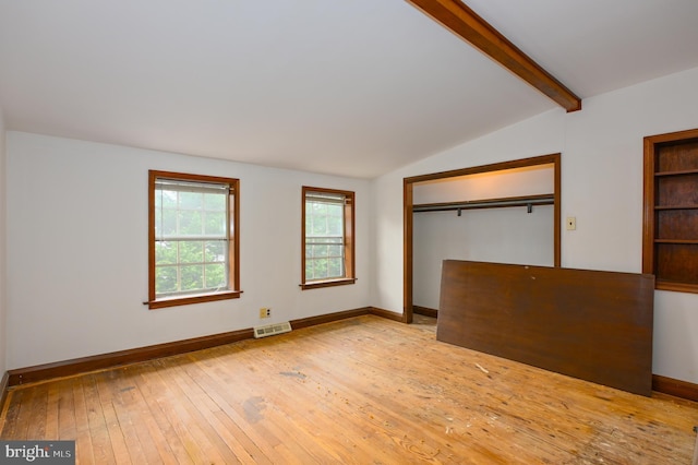 unfurnished bedroom with a closet, lofted ceiling with beams, and light hardwood / wood-style floors