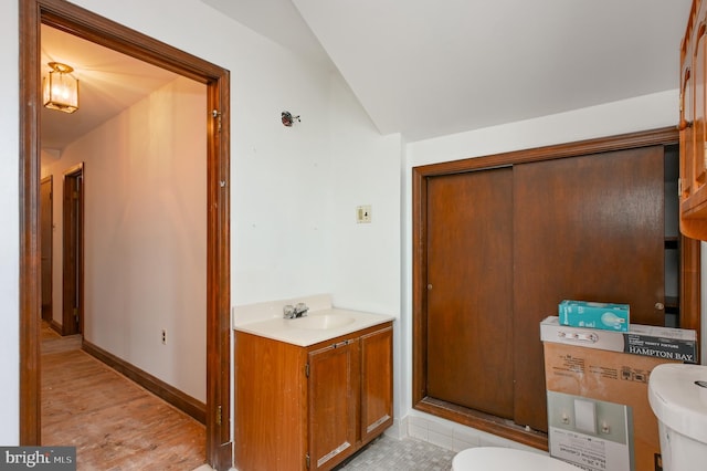 bathroom featuring toilet, hardwood / wood-style floors, vanity, and vaulted ceiling