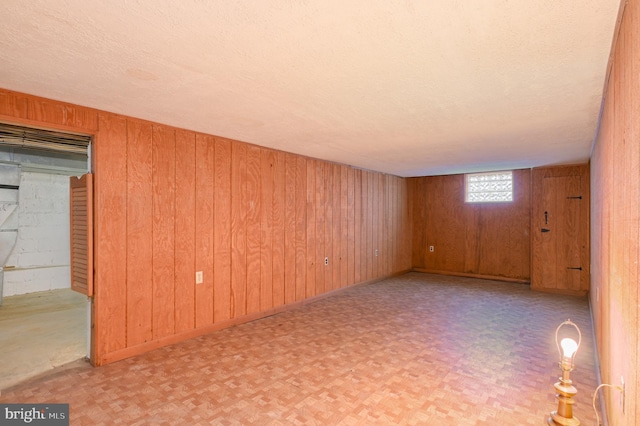 empty room with wood walls and a textured ceiling