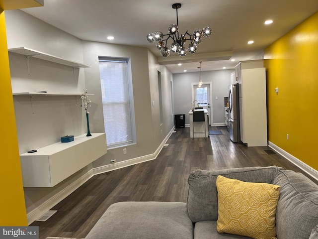 living room with a chandelier, dark wood-type flooring, and sink