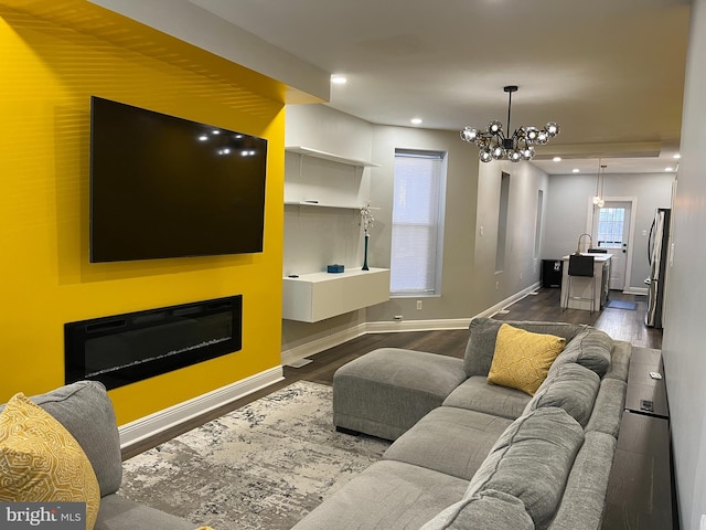 living room with sink, a chandelier, and dark hardwood / wood-style floors