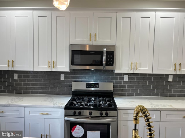 kitchen featuring tasteful backsplash, light stone counters, white cabinets, and stainless steel appliances