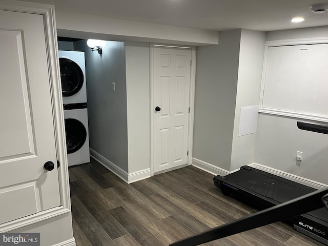 exercise room featuring stacked washer and dryer and dark wood-type flooring