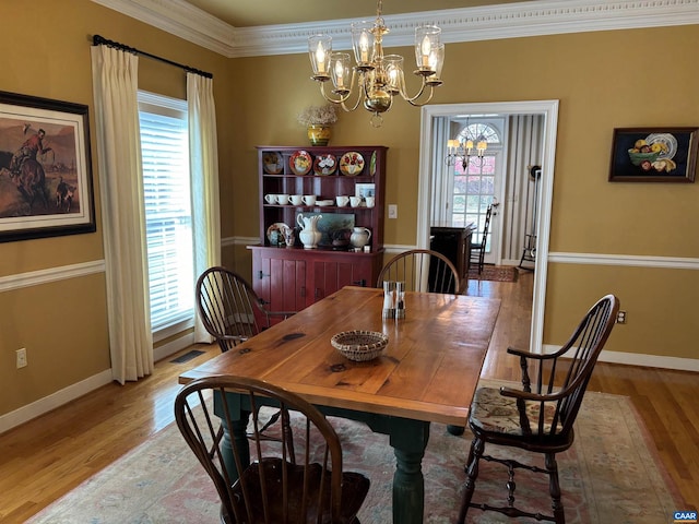 dining room featuring a chandelier, crown molding, a healthy amount of sunlight, and wood-type flooring