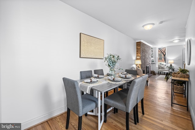 dining space with a fireplace and wood-type flooring