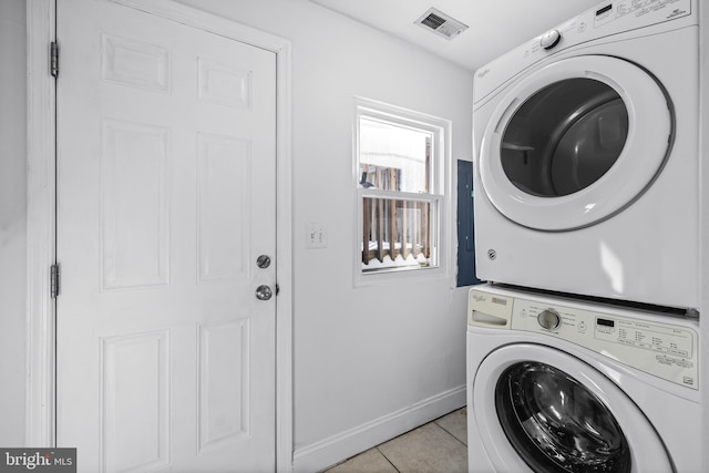 laundry room with stacked washer / dryer and light tile patterned flooring