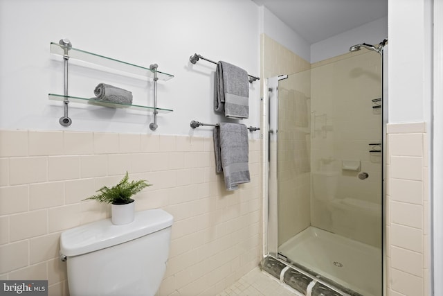 bathroom featuring a tile shower, toilet, and tile walls