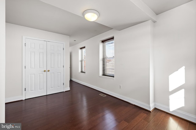 unfurnished bedroom with a closet and dark wood-type flooring