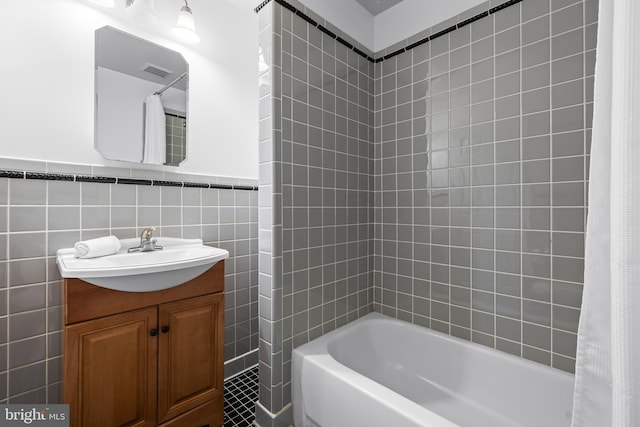 bathroom featuring vanity, shower / bath combination with curtain, and tile walls