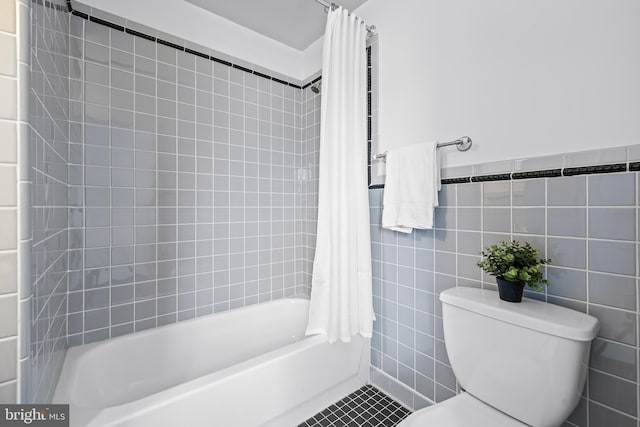 bathroom with toilet, tile patterned flooring, shower / tub combo with curtain, and tile walls