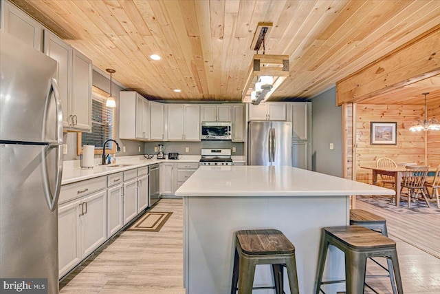 kitchen featuring a kitchen island, a kitchen bar, hanging light fixtures, and appliances with stainless steel finishes