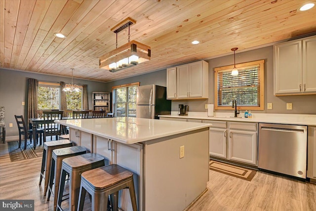 kitchen featuring a wealth of natural light, a kitchen island, decorative light fixtures, and appliances with stainless steel finishes