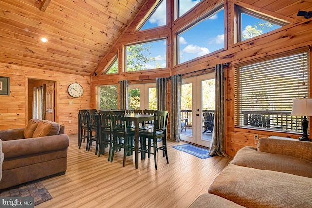 dining area featuring french doors, light wood-type flooring, wooden walls, high vaulted ceiling, and wooden ceiling