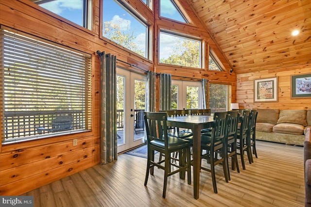 dining room with french doors, wooden walls, light hardwood / wood-style flooring, high vaulted ceiling, and wooden ceiling