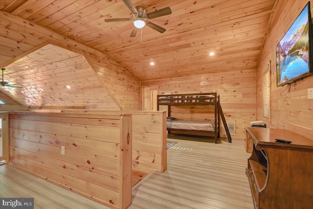 unfurnished bedroom featuring wood walls, vaulted ceiling, ceiling fan, light wood-type flooring, and wood ceiling