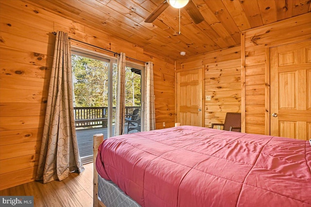 bedroom with access to exterior, ceiling fan, wood-type flooring, wooden ceiling, and wood walls