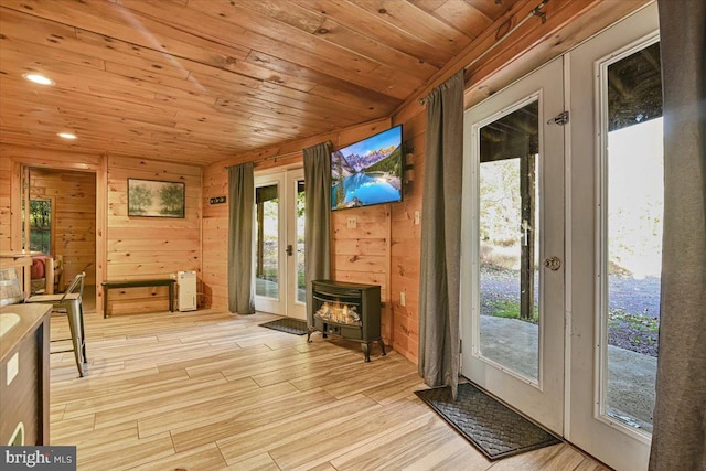 doorway to outside with french doors, light hardwood / wood-style flooring, and a wood stove