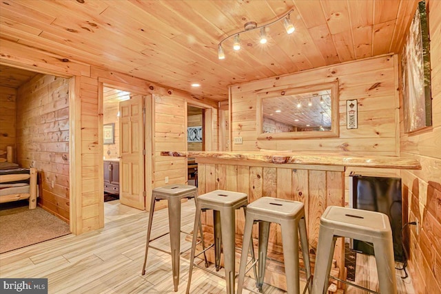 bar featuring wooden walls, light hardwood / wood-style flooring, and wooden ceiling