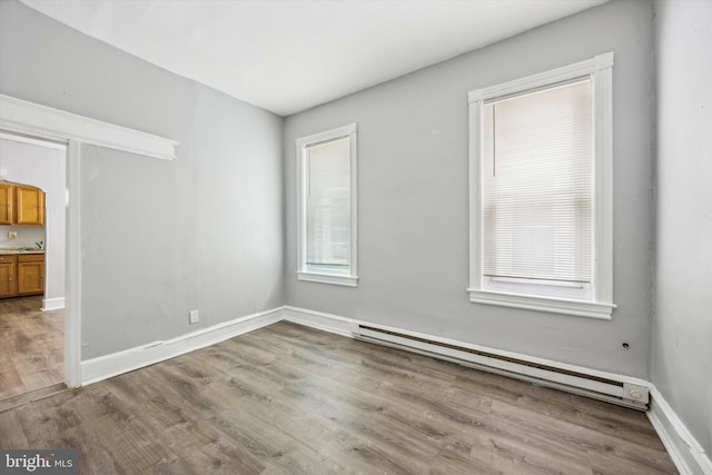 spare room featuring a baseboard radiator and wood-type flooring