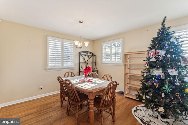 dining area with wood-type flooring and a notable chandelier