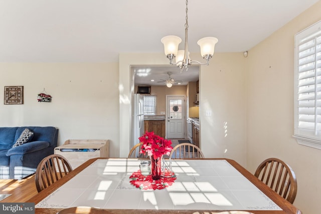 dining space featuring ceiling fan with notable chandelier and hardwood / wood-style flooring