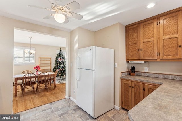 kitchen with ceiling fan with notable chandelier, white refrigerator, light hardwood / wood-style flooring, and hanging light fixtures