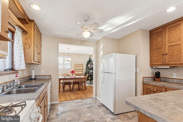 kitchen featuring sink, hanging light fixtures, light hardwood / wood-style floors, white appliances, and ceiling fan with notable chandelier