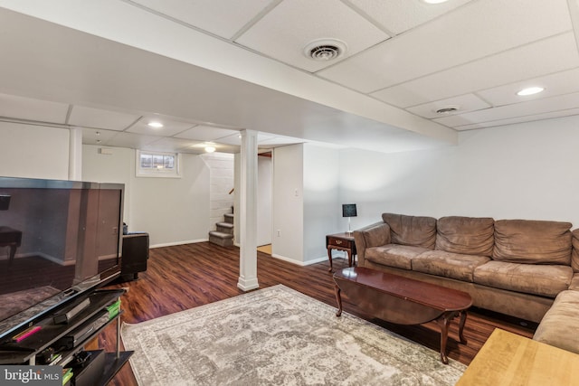 living room featuring a drop ceiling and dark wood-type flooring