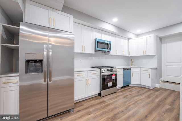 kitchen featuring white cabinets, sink, decorative backsplash, light wood-type flooring, and stainless steel appliances