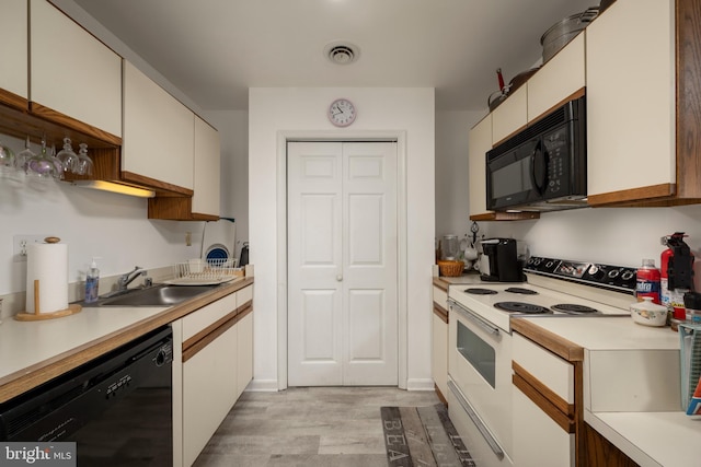 kitchen with white cabinets, sink, light hardwood / wood-style flooring, and black appliances