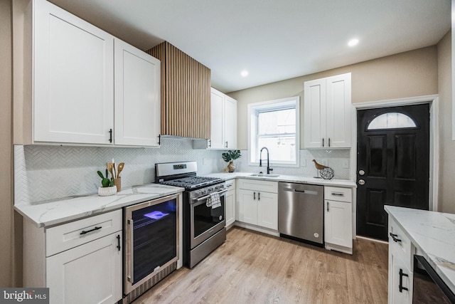 kitchen with white cabinets, stainless steel appliances, wine cooler, and light hardwood / wood-style floors