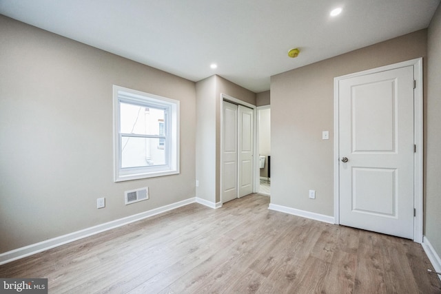 unfurnished bedroom featuring light wood-type flooring and a closet