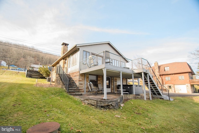 back of property featuring a lawn, a wooden deck, and a patio