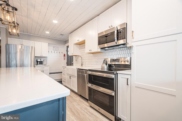 kitchen featuring tasteful backsplash, white cabinetry, light wood-type flooring, and appliances with stainless steel finishes