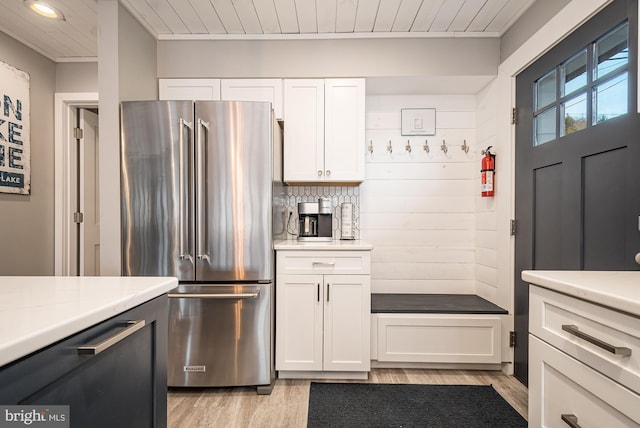 kitchen featuring wooden ceiling, light wood-type flooring, tasteful backsplash, high end fridge, and white cabinetry