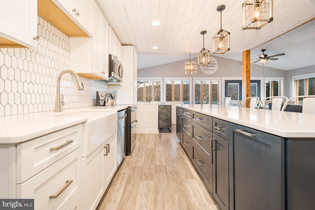 kitchen featuring vaulted ceiling, decorative light fixtures, white cabinetry, and ceiling fan