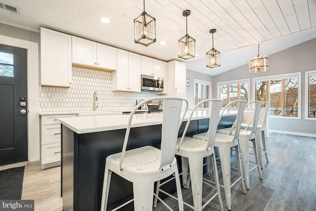 kitchen featuring decorative light fixtures, white cabinets, a healthy amount of sunlight, and lofted ceiling