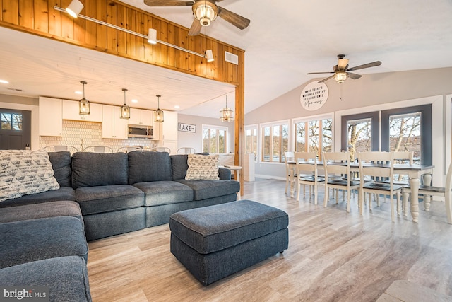 living room with ceiling fan, a healthy amount of sunlight, and vaulted ceiling