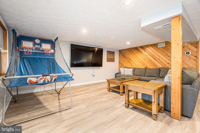 living room with wood walls, hardwood / wood-style floors, and a textured ceiling