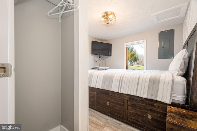 bedroom with wood-type flooring, a textured ceiling, and electric panel