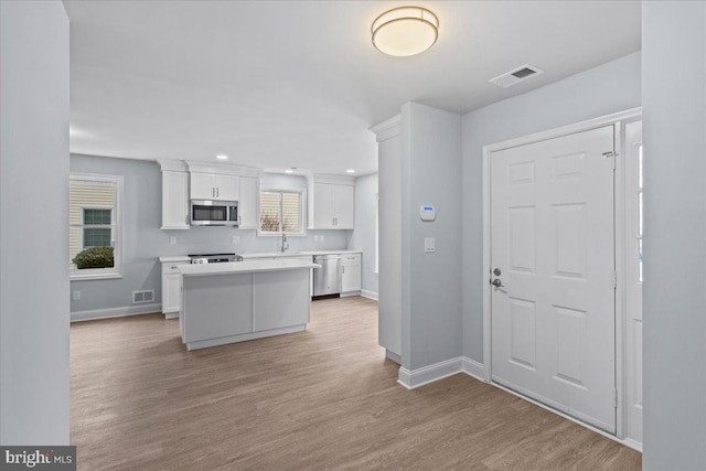 kitchen featuring white cabinetry, sink, a center island, stainless steel appliances, and light wood-type flooring