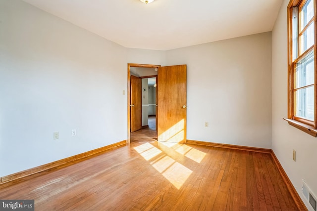 empty room with a healthy amount of sunlight and light hardwood / wood-style flooring