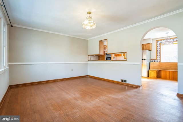 unfurnished room featuring crown molding, light hardwood / wood-style floors, and a chandelier